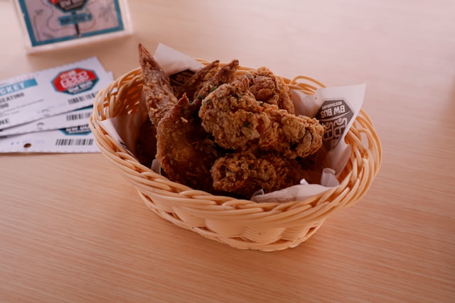 テーブルの上のカゴにたくさんのフライドチキンが入っている画像